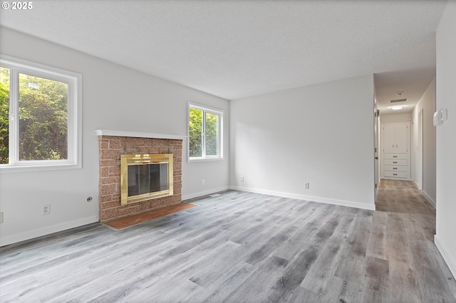 245 NE 4th Ave, Hillsboro, OR 97124 - unfurnished living room featuring wood finished floors, a brick fireplace, baseboards, and a textured ceiling