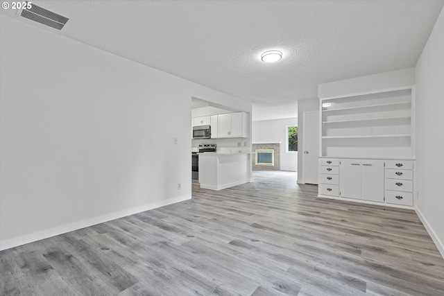 245 NE 4th Ave, Hillsboro, OR 97124 - unfurnished living room with a textured ceiling, light wood-style flooring, and baseboards