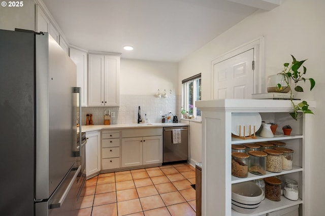 909 NE Brazee St Unit 16, Portland, OR 97212 - kitchen featuring appliances with stainless steel finishes, light countertops, white cabinetry, decorative backsplash, and light tile patterned floors