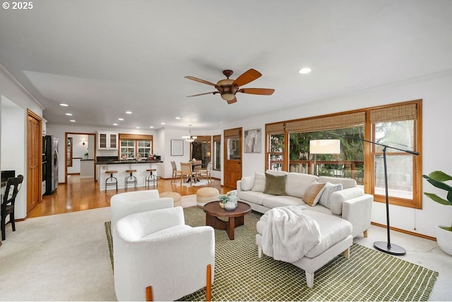 living room featuring ceiling fan, light wood-type flooring, and crown molding