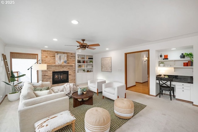 living room with built in shelves, a fireplace, built in desk, and ornamental molding