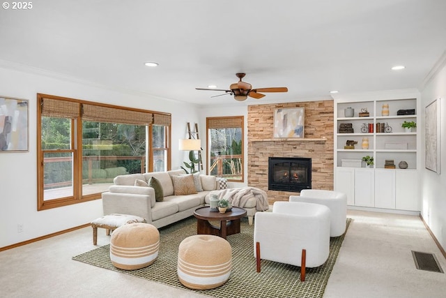 living room featuring a tile fireplace, a wealth of natural light, ornamental molding, and ceiling fan