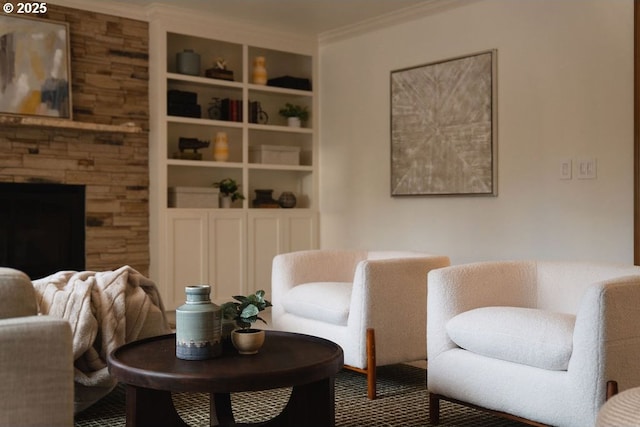 living area with built in shelves, crown molding, and a fireplace