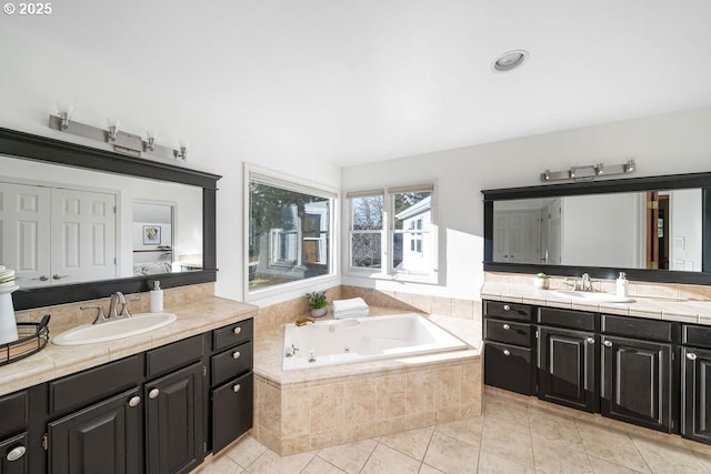 bathroom with tile patterned floors, vanity, and tiled tub