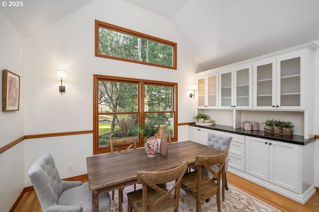 dining area with light hardwood / wood-style floors and high vaulted ceiling