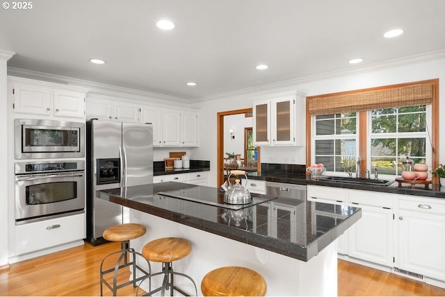 kitchen with sink, a kitchen breakfast bar, white cabinets, a kitchen island, and appliances with stainless steel finishes