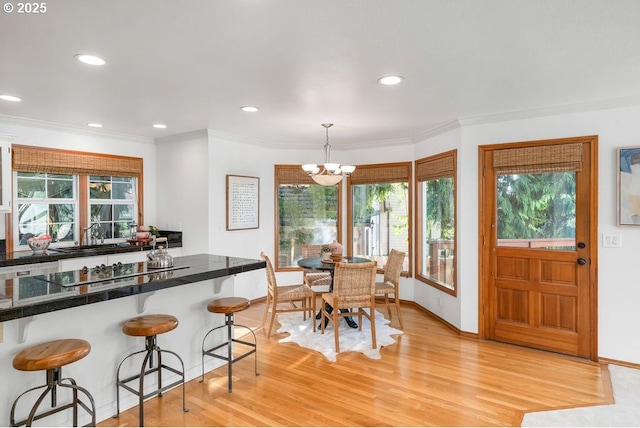 kitchen with an inviting chandelier, light hardwood / wood-style flooring, decorative light fixtures, a breakfast bar area, and black electric cooktop