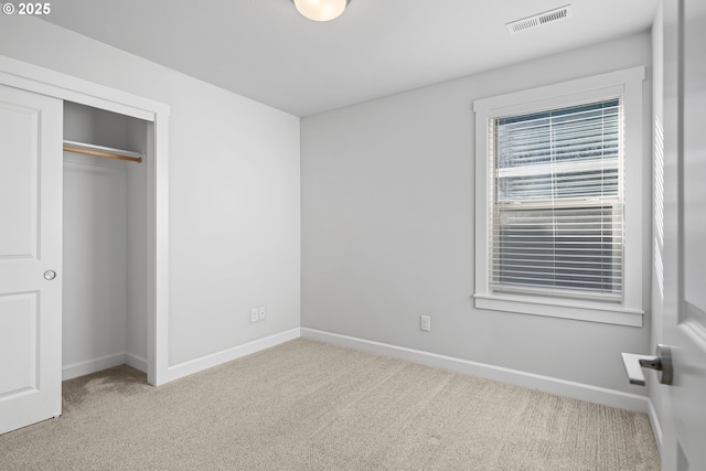 unfurnished bedroom with carpet floors, a closet, visible vents, and baseboards