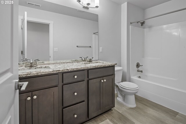 full bathroom featuring toilet, a sink, wood finished floors, visible vents, and double vanity