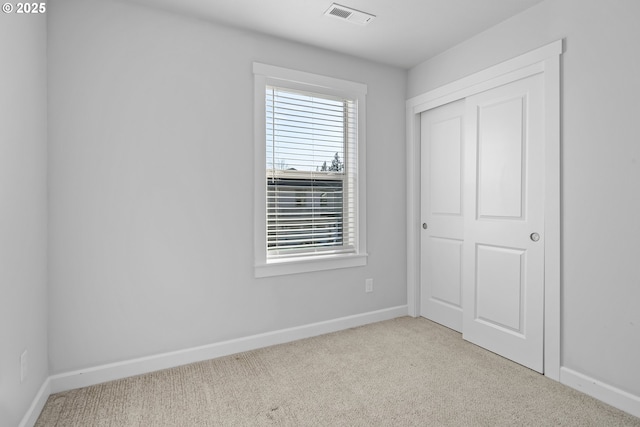 unfurnished bedroom with a closet, baseboards, visible vents, and carpet flooring