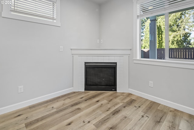 unfurnished living room featuring a fireplace, wood finished floors, and baseboards