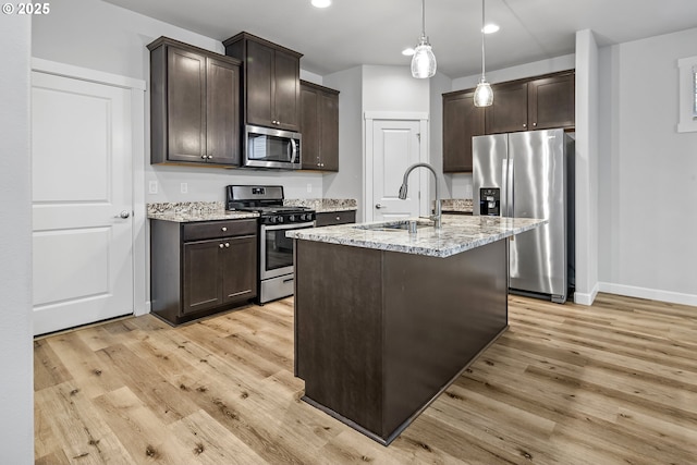 kitchen featuring stainless steel appliances, dark brown cabinets, light wood-type flooring, and light stone countertops