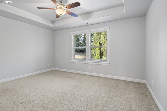 unfurnished room featuring ceiling fan, light carpet, visible vents, baseboards, and a raised ceiling