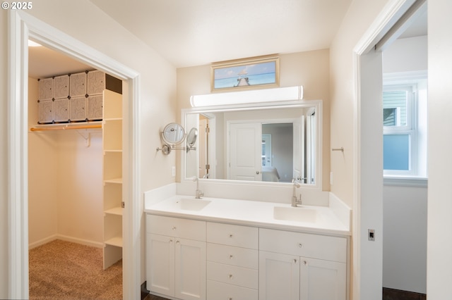 bathroom with a sink, a spacious closet, and double vanity