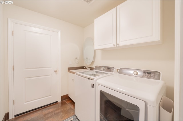 clothes washing area with cabinet space, independent washer and dryer, and a sink