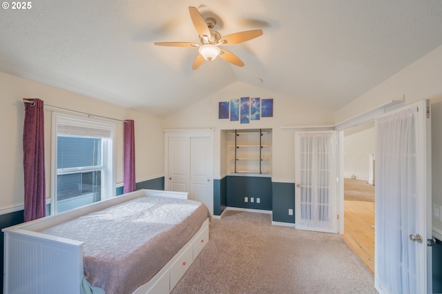 carpeted bedroom with a ceiling fan, lofted ceiling, a closet, and baseboards