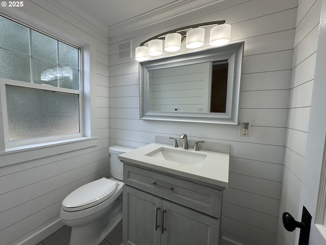 212 NW Bridge St, John Day, OR 97845 - half bath featuring toilet, vanity, ornamental molding, and wood walls