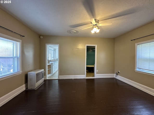 212 NW Bridge St, John Day, OR 97845 - spare room featuring dark wood-style floors, heating unit, ceiling fan, baseboards, and a sink