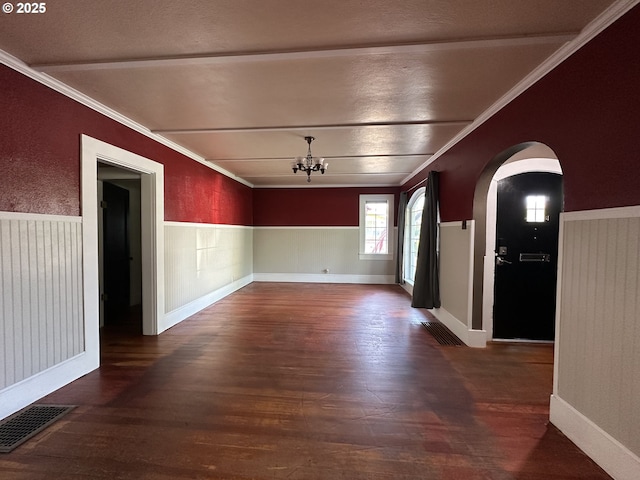212 NW Bridge St, John Day, OR 97845 - empty room with dark wood-style floors, a chandelier, arched walkways, crown molding, and a wainscoted wall