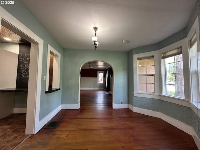 212 NW Bridge St, John Day, OR 97845 - unfurnished dining area featuring wood finished floors, arched walkways, a chandelier, and baseboards