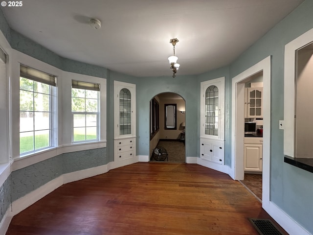 212 NW Bridge St, John Day, OR 97845 - unfurnished dining area featuring arched walkways, baseboards, and wood finished floors