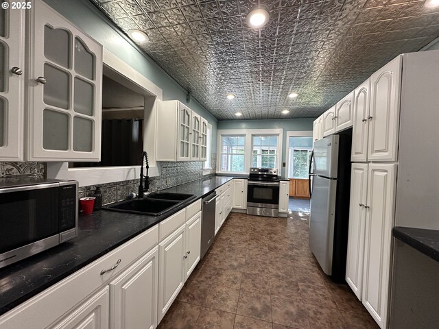 212 NW Bridge St, John Day, OR 97845 - kitchen with appliances with stainless steel finishes, a sink, an ornate ceiling, white cabinetry, and glass insert cabinets