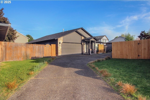 view of front of home featuring fence, a front lawn, aphalt driveway, a garage, and a gate