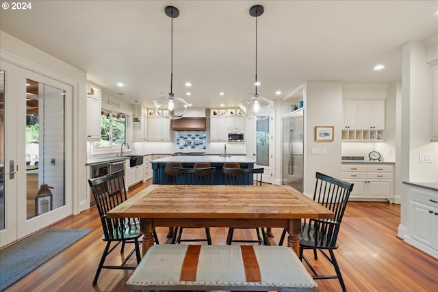 dining room featuring light wood-type flooring, french doors, and sink