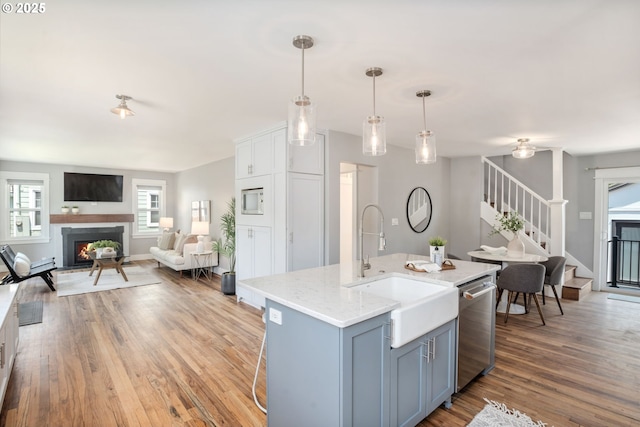 6126 SE 23rd Ave, Portland, OR 97202 - kitchen featuring stainless steel dishwasher, open floor plan, light wood-style flooring, a lit fireplace, and decorative light fixtures