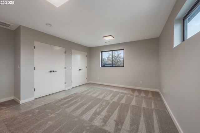 unfurnished bedroom featuring multiple closets and carpet floors