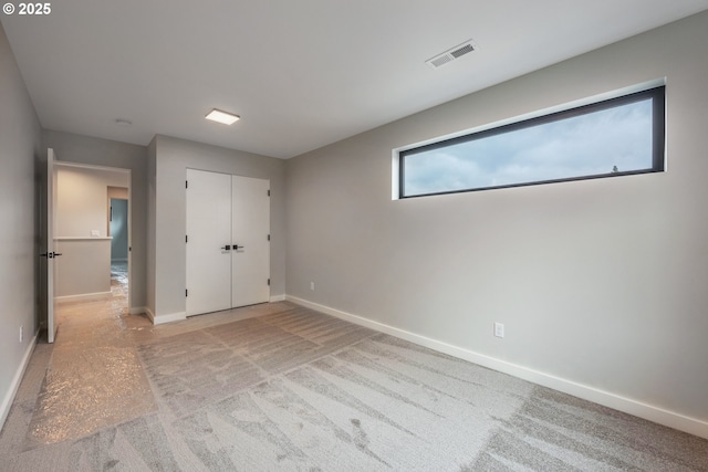 unfurnished bedroom featuring light colored carpet and a closet