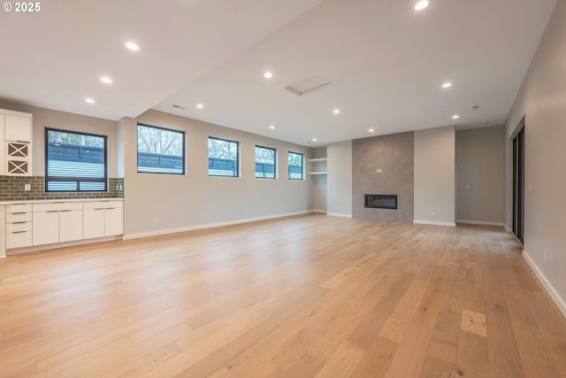 unfurnished living room featuring a tiled fireplace and light hardwood / wood-style flooring