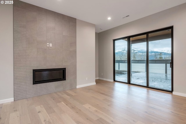 unfurnished living room with a fireplace and light wood-type flooring