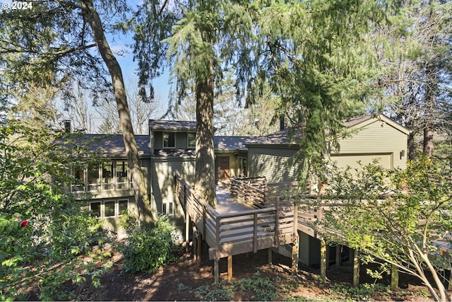 rear view of house featuring a garage and a wooden deck