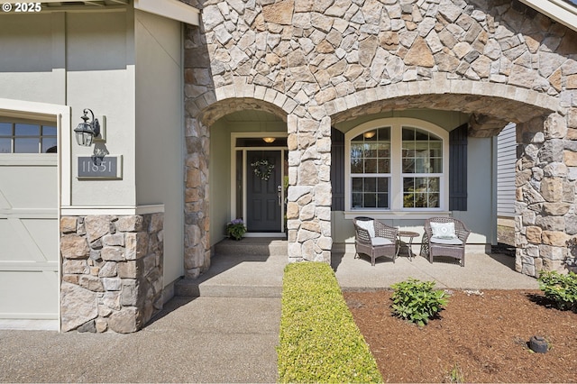 entrance to property with stone siding, covered porch, and a garage