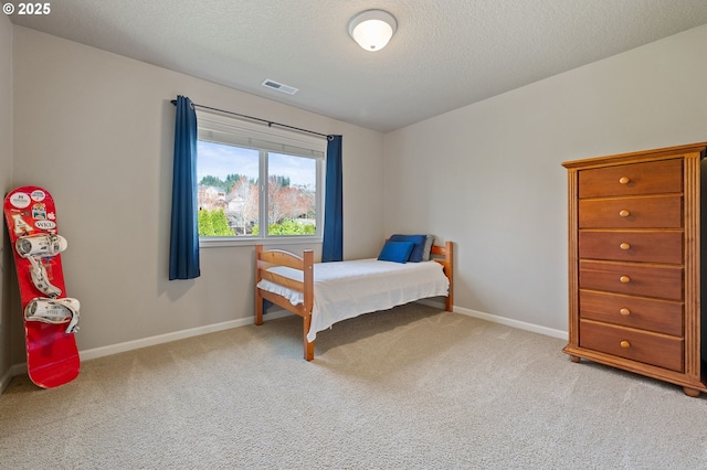 carpeted bedroom with visible vents, baseboards, and a textured ceiling