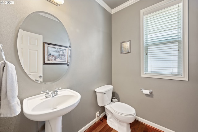 bathroom featuring baseboards, a sink, ornamental molding, toilet, and wood finished floors