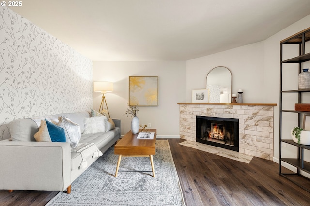 living room with a fireplace with flush hearth, baseboards, and wood finished floors