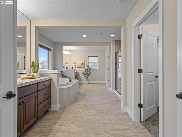 bathroom featuring independent shower and bath, vanity, and a textured ceiling