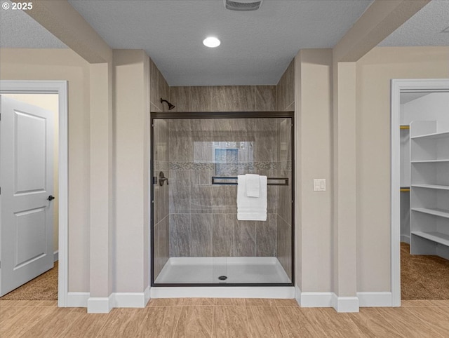 full bathroom with a stall shower, baseboards, and a textured ceiling