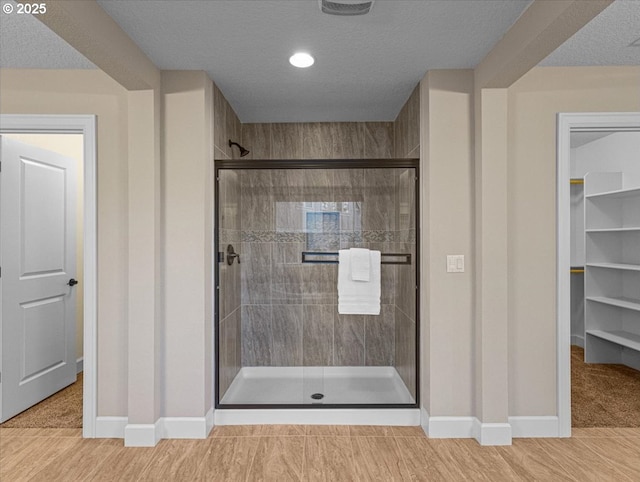 bathroom featuring a shower with shower door and a textured ceiling