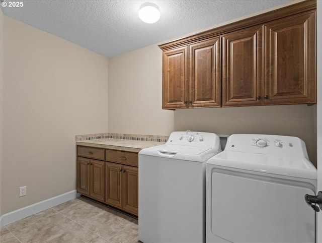 clothes washing area featuring light tile patterned floors, baseboards, a textured ceiling, cabinet space, and washing machine and dryer