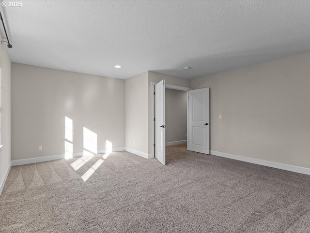 carpeted spare room featuring baseboards and a textured ceiling