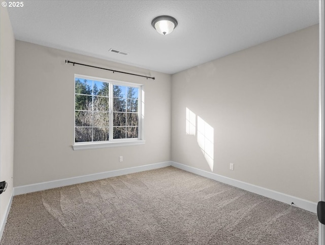 carpeted spare room with visible vents, baseboards, and a textured ceiling