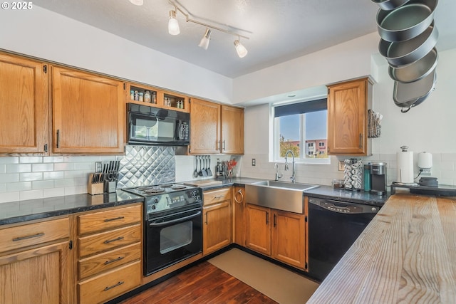 kitchen featuring backsplash, brown cabinets, dark wood-style floors, black appliances, and a sink