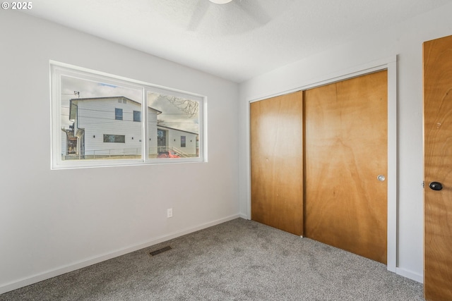 unfurnished bedroom featuring baseboards, visible vents, carpet floors, ceiling fan, and a closet