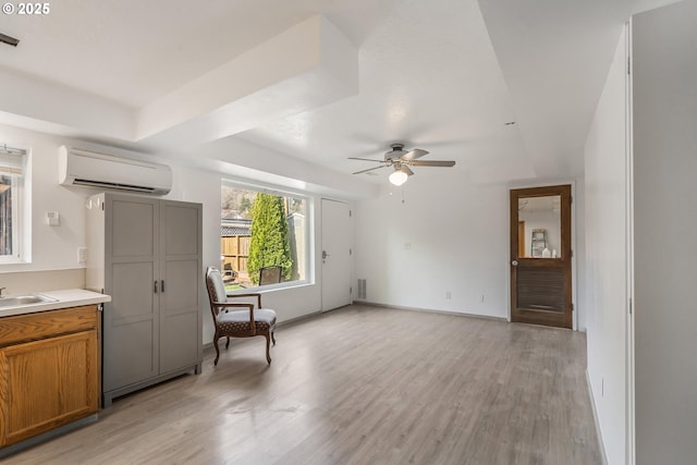 living area with baseboards, light wood-style floors, ceiling fan, and a wall mounted AC