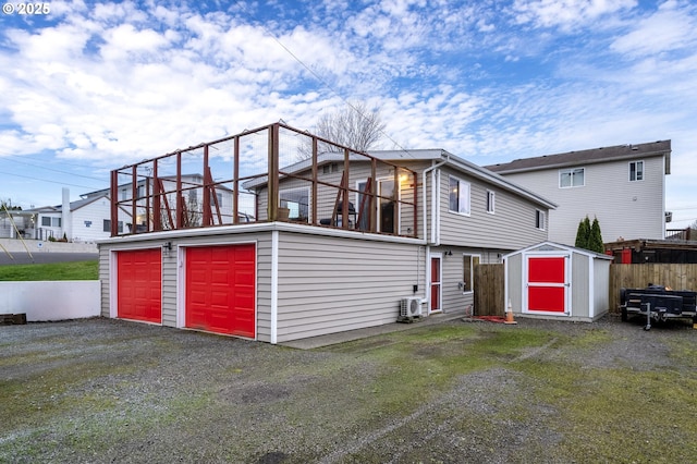 exterior space with driveway, a shed, fence, an outdoor structure, and a garage