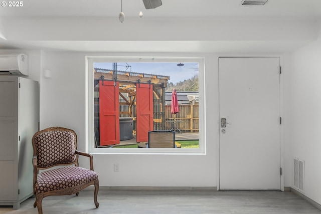 living area featuring visible vents, a wall mounted air conditioner, and wood finished floors