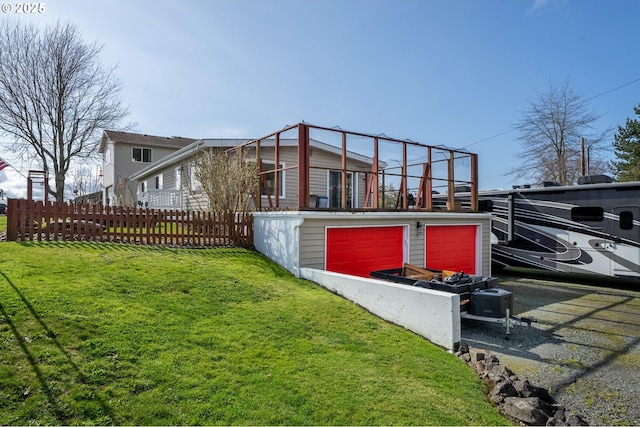 rear view of property featuring a lawn and fence